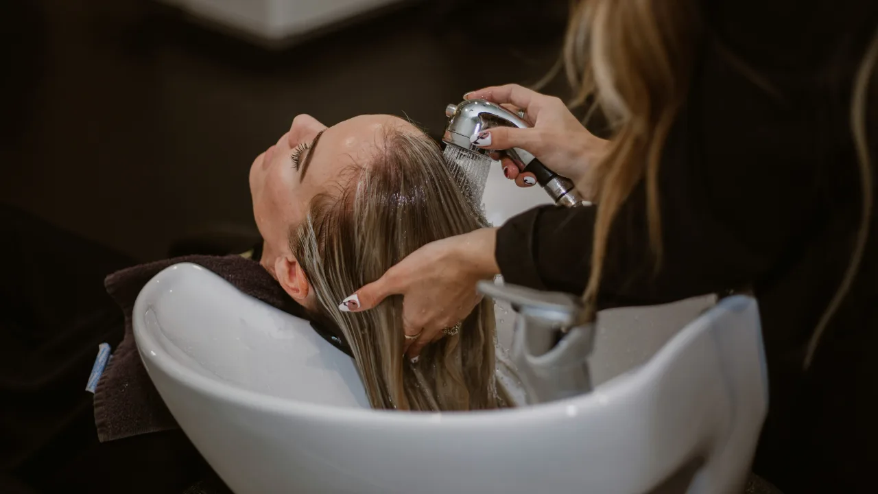 Stylist washing a client's hair at a salon basin