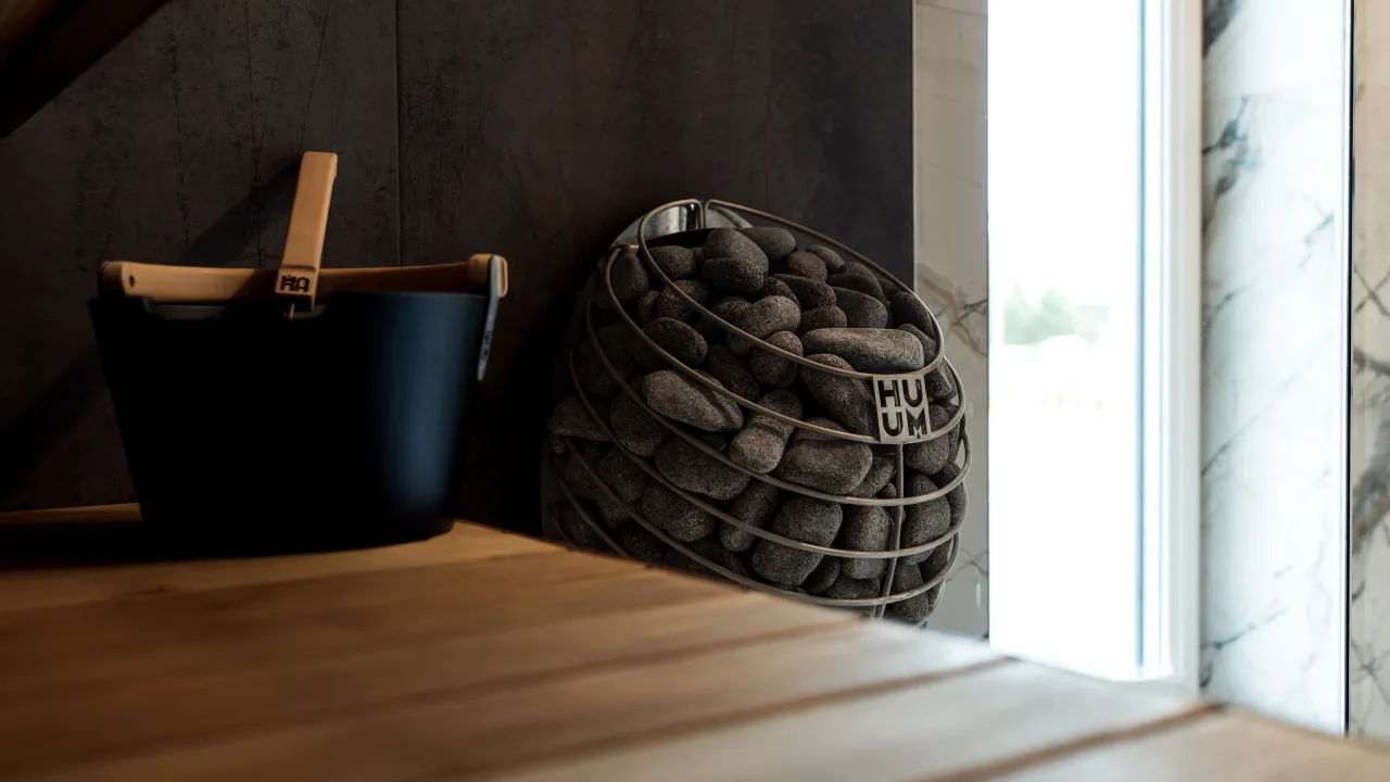 Sauna heater filled with stones beside a wooden bench