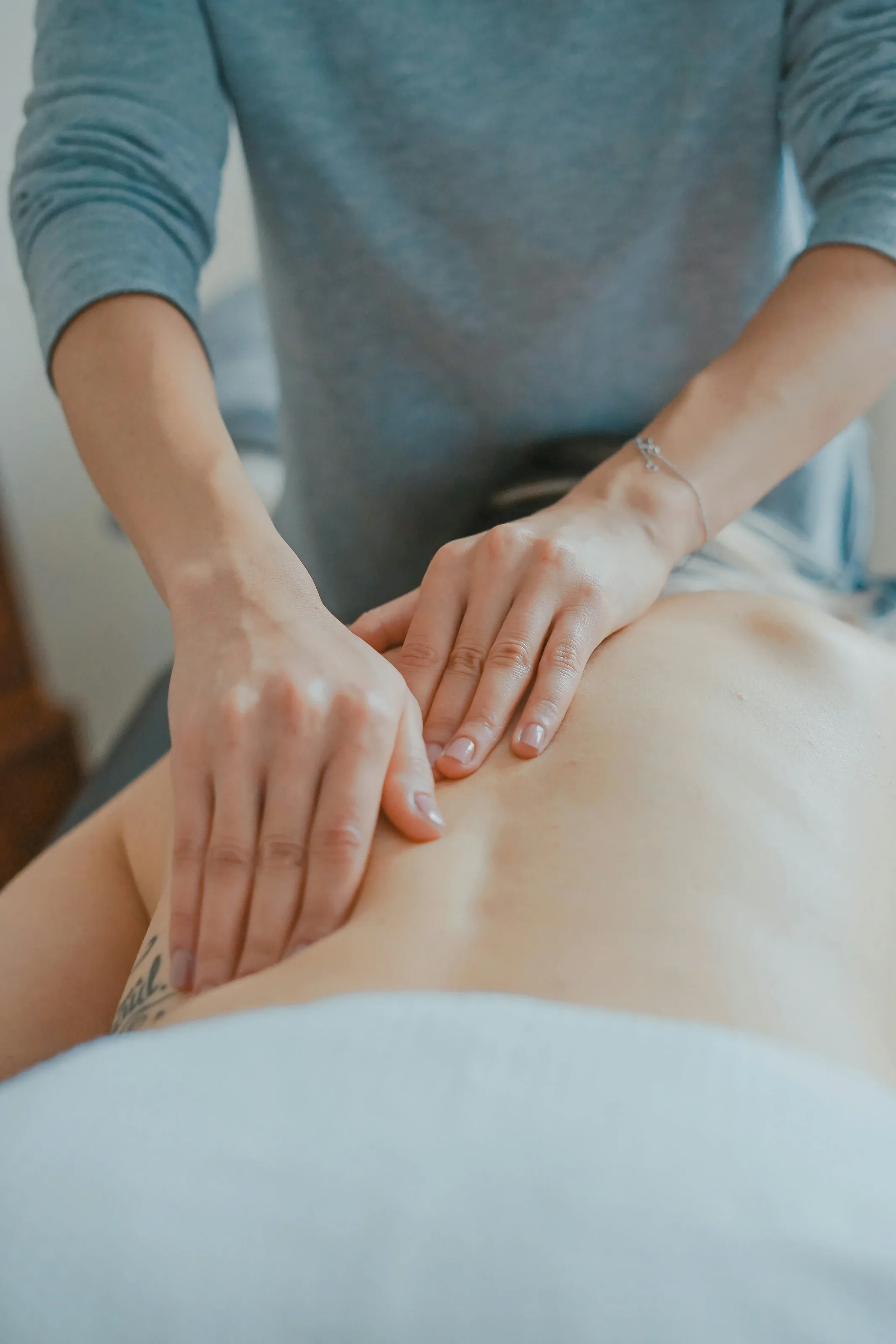 Close-up of a therapist's hands massaging a client's shoulders